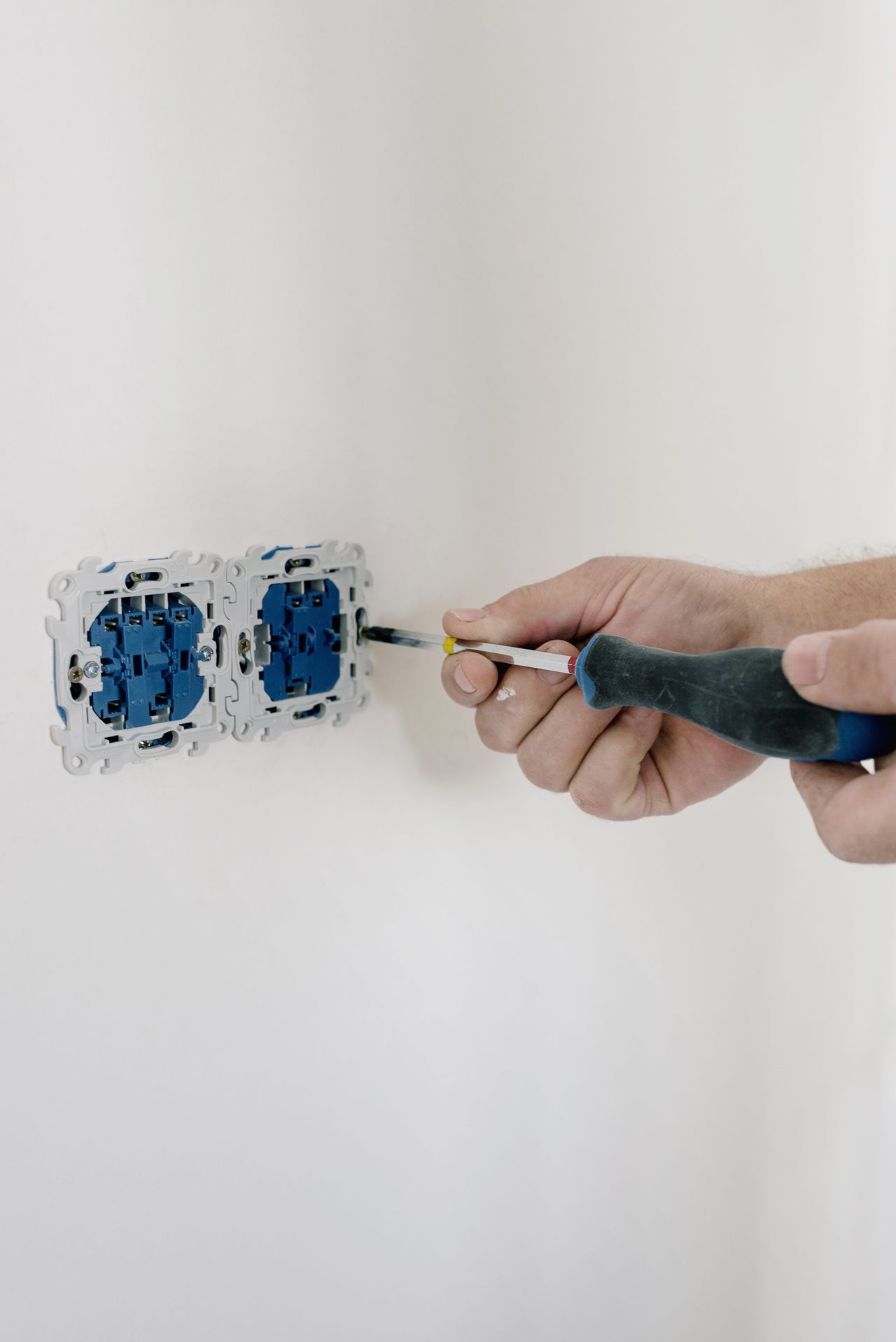 Elektroarbeiten – Monteur montiert mit dem Schraubendreher eine Doppelsteckdose in der Wand