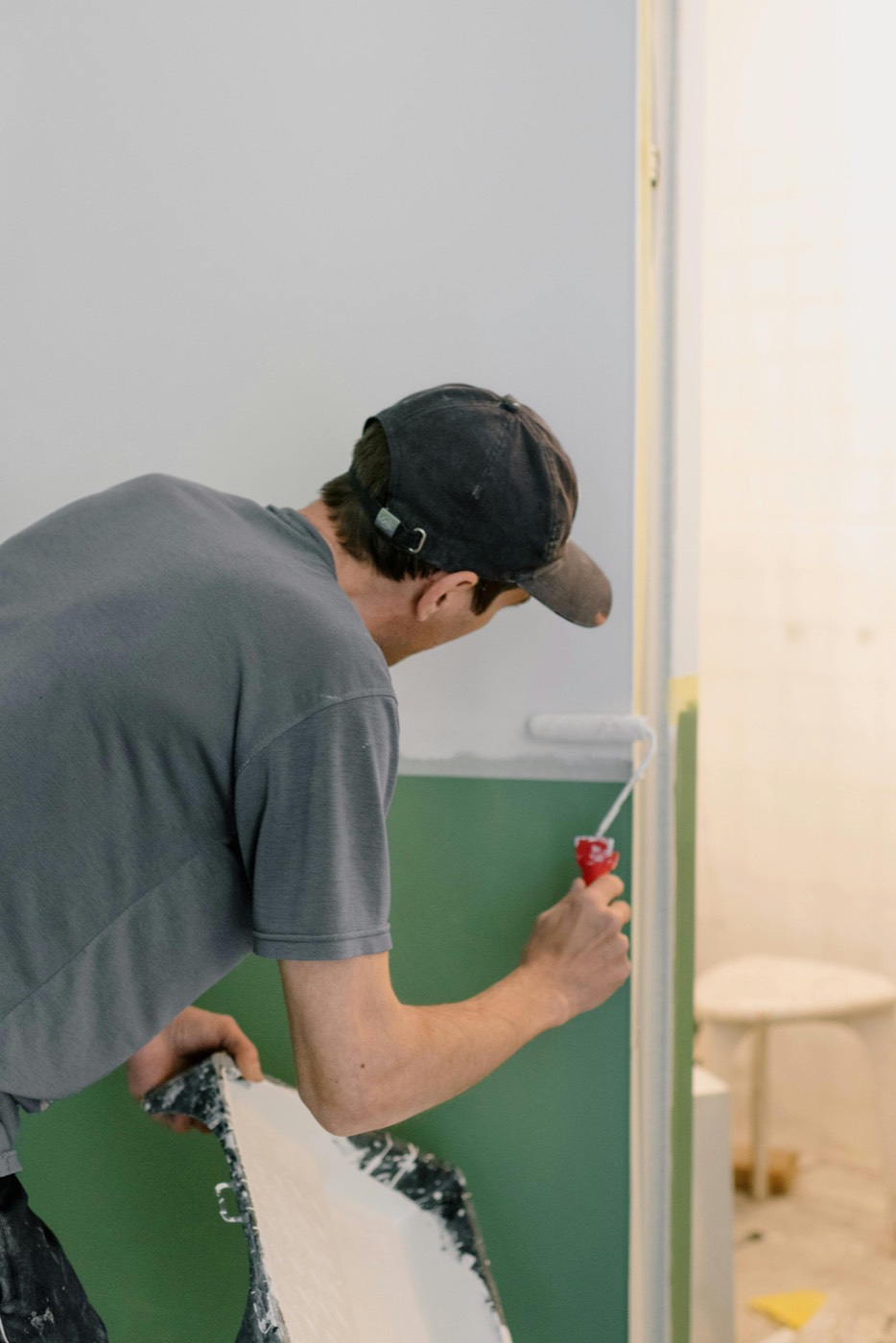 Malerarbeiten – Handwerker streicht eine Wand mit der Farbrolle