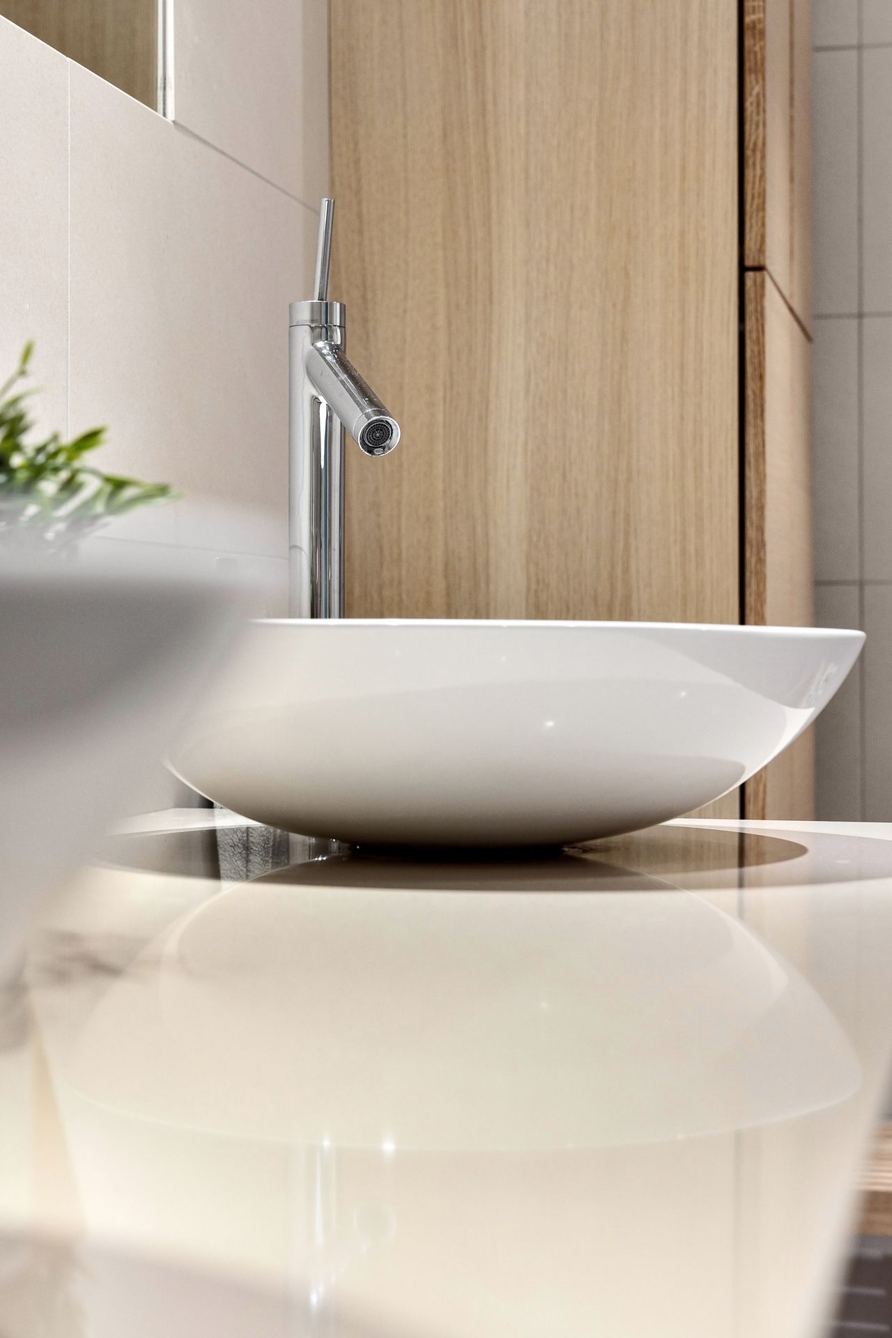 Sanitärarbeiten – moderner Waschtisch mit verchromter Armatur in einem fertig gefliesten Bad